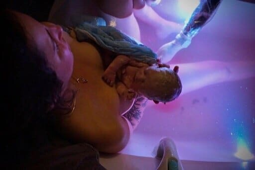 Water birth with midwife delivering placenta.