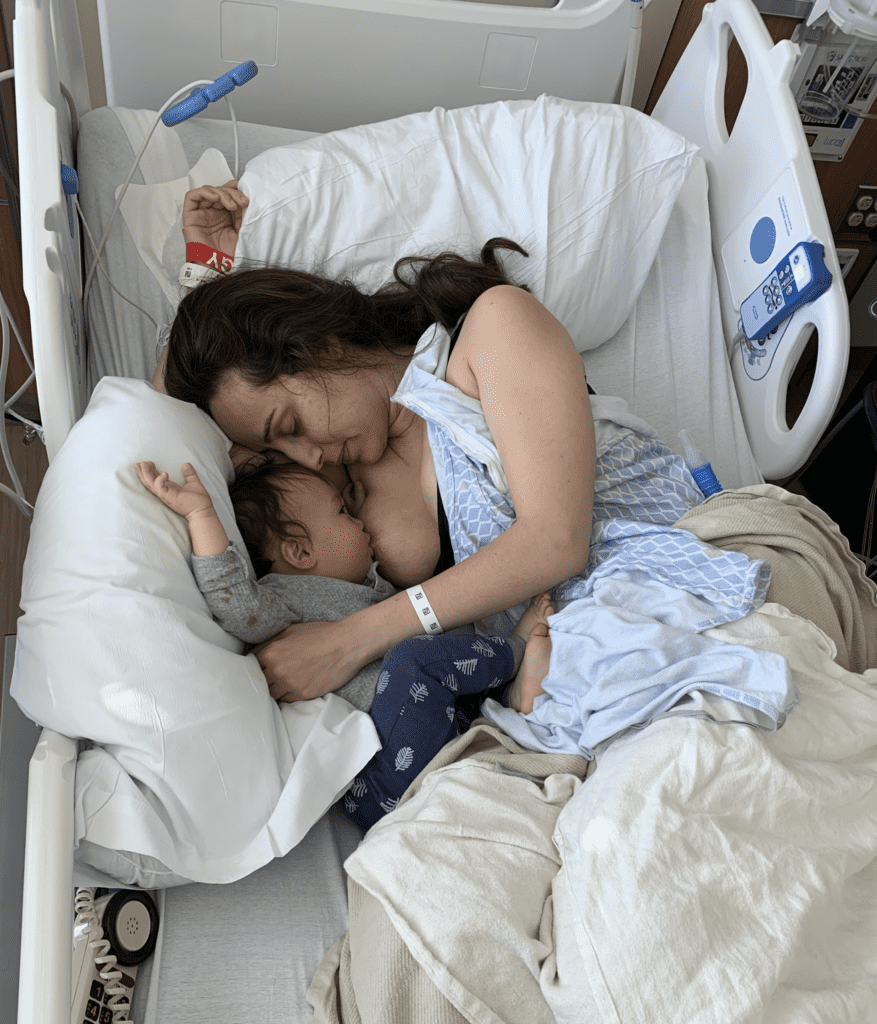 Mom and baby breastfeeding in hospital bed.